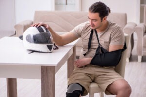 young male motorcycle rider with his arm in a sling and his helmet next to him on the table